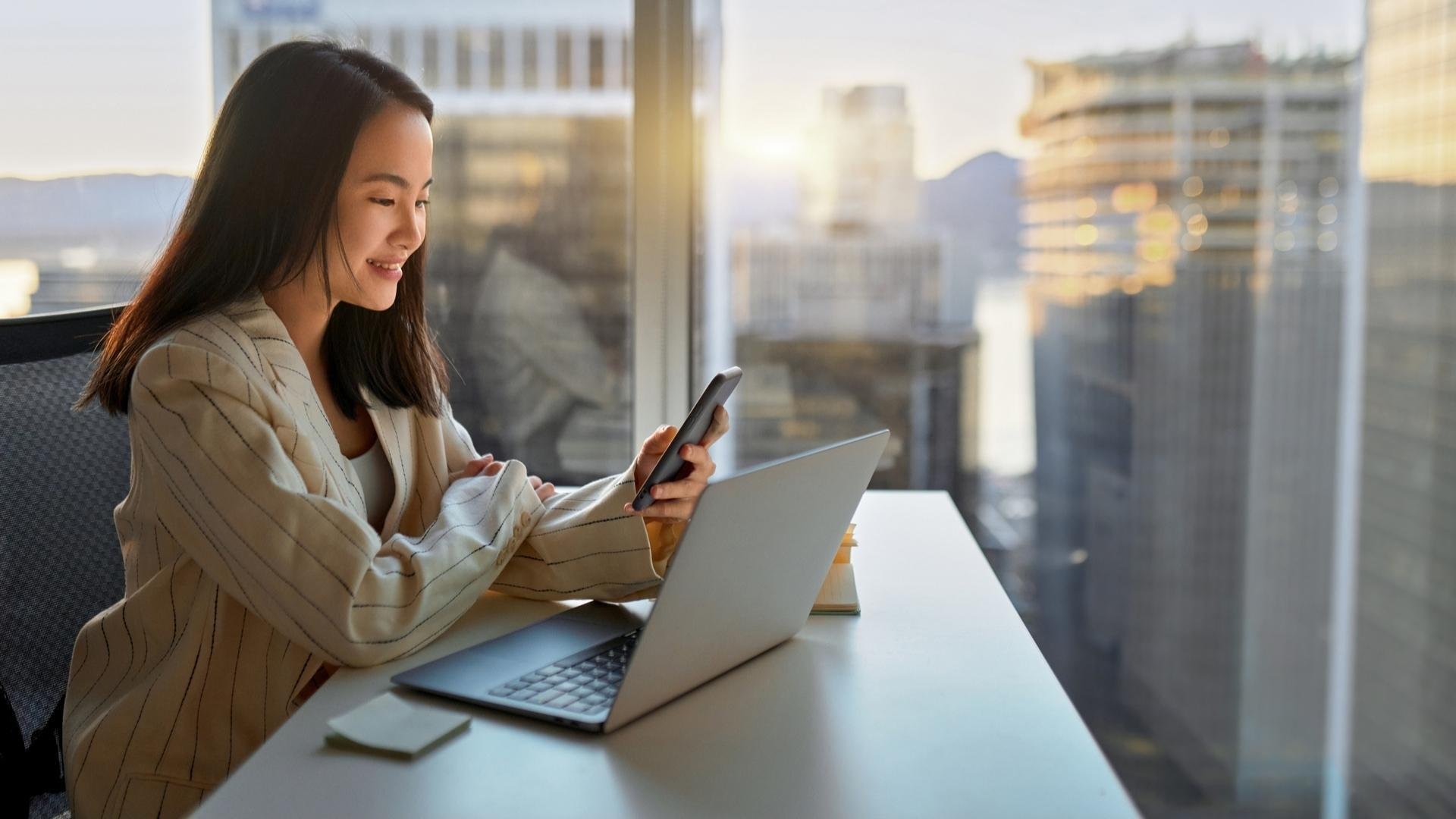 Consumer-electronics-chinese-woman-with-notebook-and-smartphone-in-front-of-skyscraper