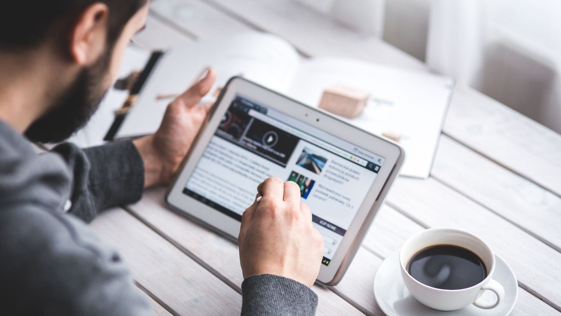 Man-browsing-news-on-tablet-backview