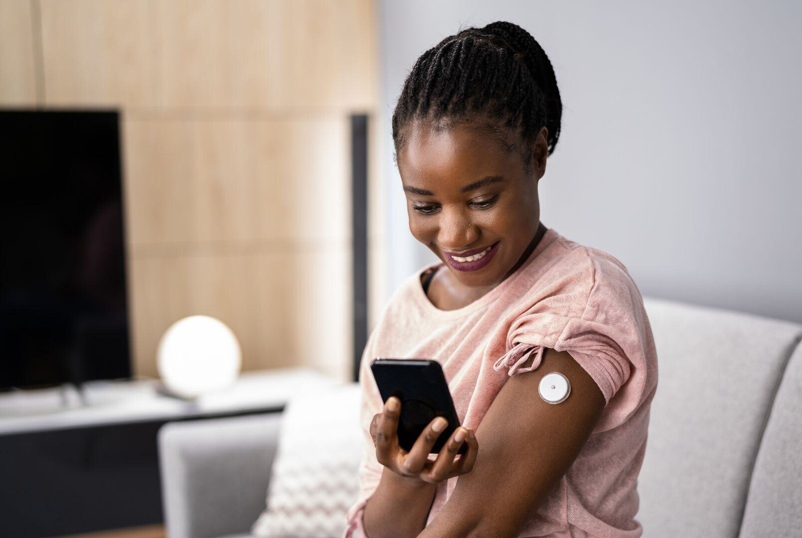 Lonwear-skin-adhesive-woman-checking-cgm-wearable-with-smartphone-left